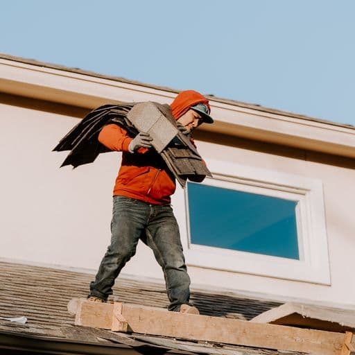 ARRT worker carrying shingles on a roof
