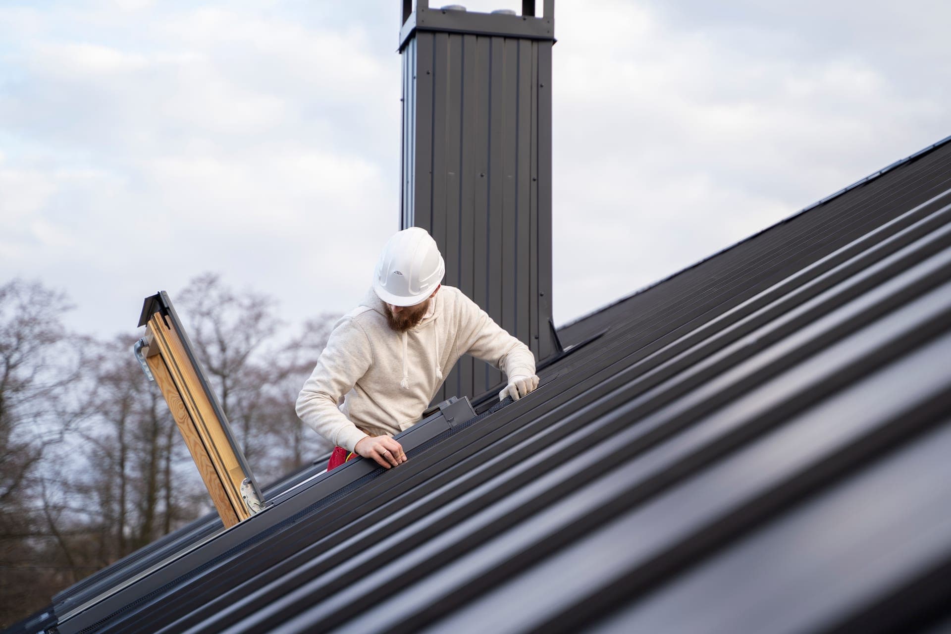 Roofer in hard hat working on a standing-seam metal roof