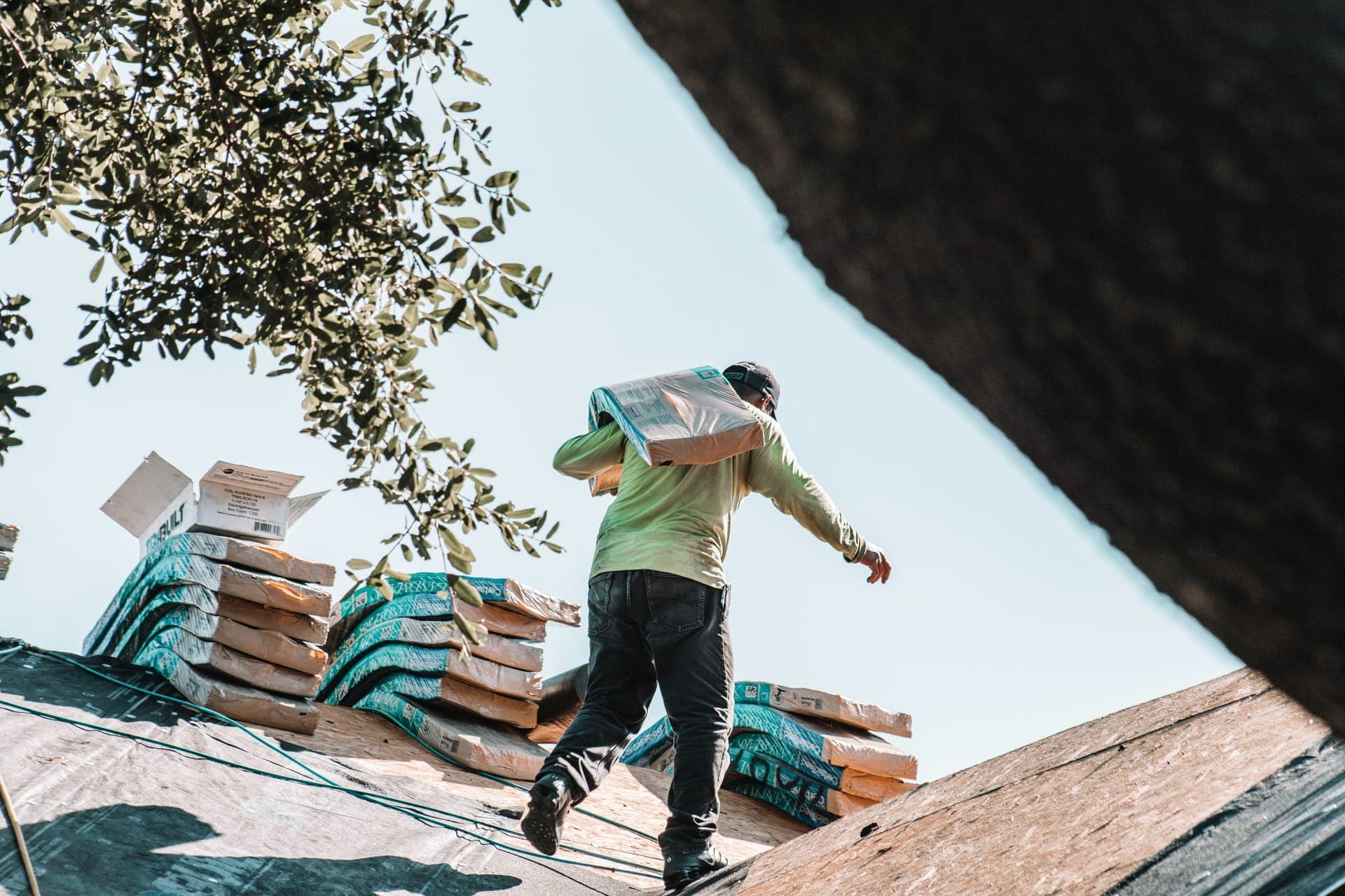 Roofer carrying shingles up a residential roof