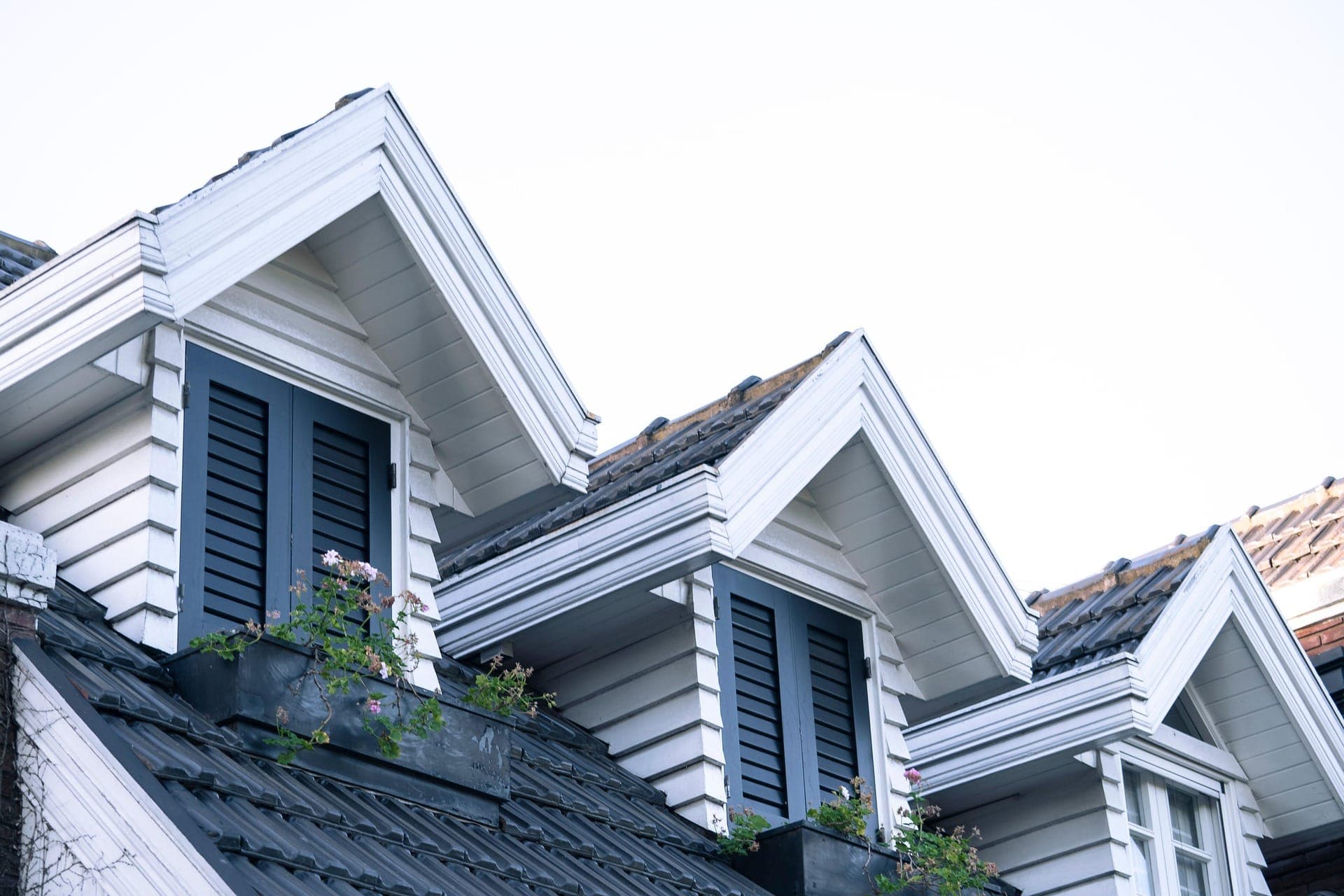 White dormers with dark tile roofing on a designer home