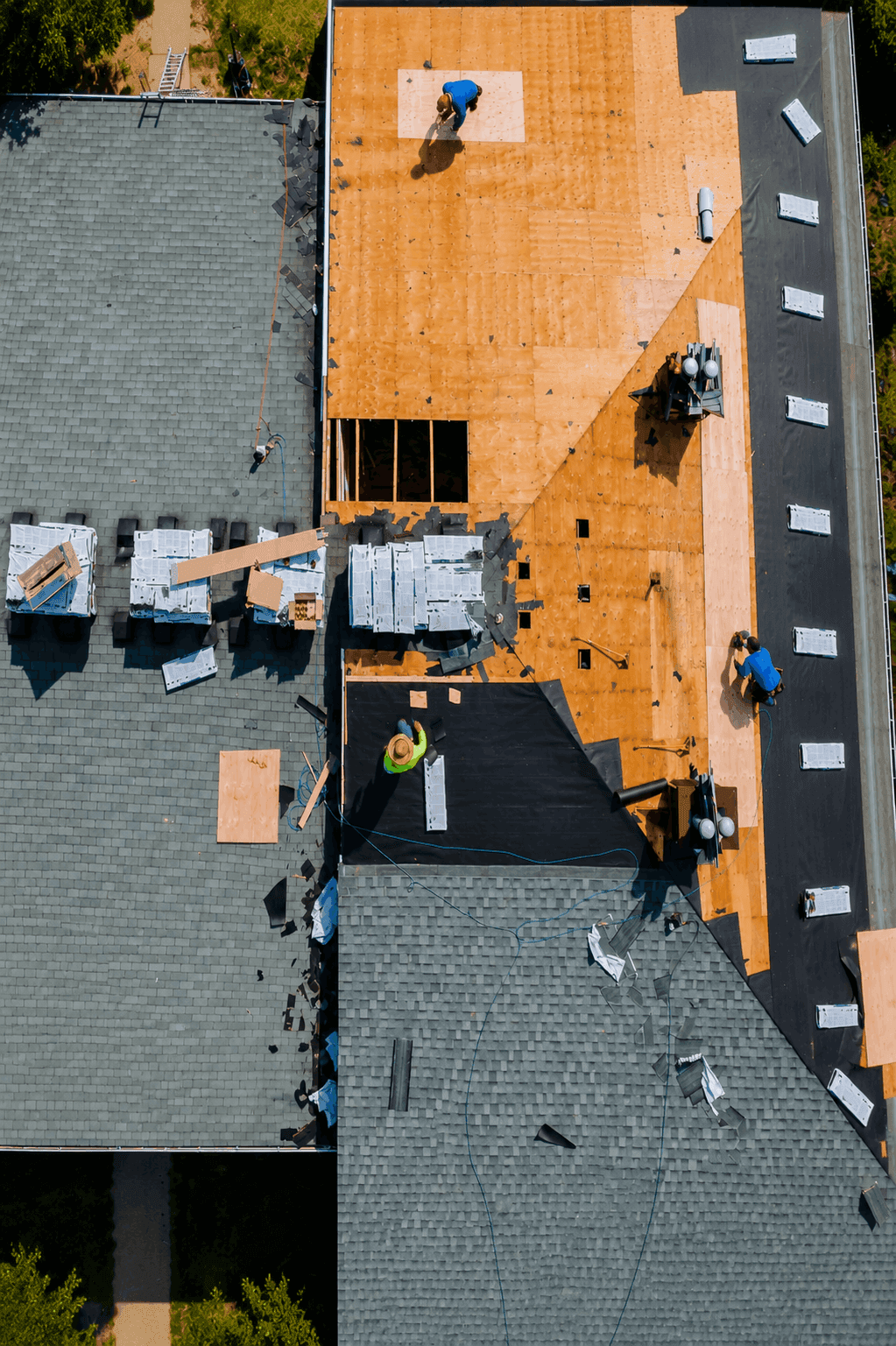 Aerial view of a roof replacement in progress with crew on the deck